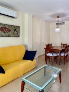 ein Wohnzimmer mit einem gelben Sofa und einem Tisch in der Unterkunft Apt Familiar con vistas al mar in L'Ametlla de Mar