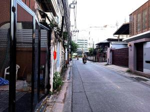 a person riding a motorcycle down a city street at OYO 75416 Rama3 Sunrise Hostel in Bangkok