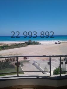 uma vista para a praia a partir de uma varanda em villa s+5 pied dans l'eau Plage Ezzahra 22993892 em Kelibia