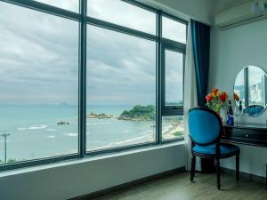 Habitación con una silla azul frente a una ventana en Paralia Hotel Nha Trang en Nha Trang