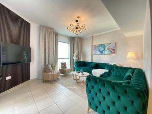 a living room with a green couch and a television at Durrani Homes - The Residences 5BR Besides Dubai Mall with Burjkhalifa and Fountain view in Dubai