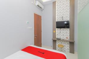 a small room with a bed and a television at RedDoorz at Ngaggel Jaya Surabaya in Surabaya