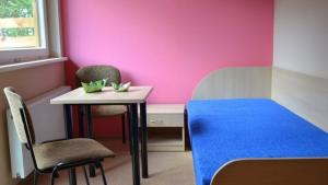 Habitación con mesa, sillas y pared de color rosa. en Poilsio bazė Draugai, en Daugai