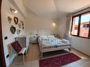een slaapkamer met een bed, een stoel en een raam bij Bilocale n 10 Arbatax vicino al mare in Àrbatax