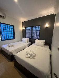 2 camas en una habitación con 2 ventanas en Archaic House, en Siem Reap