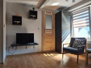 ein Wohnzimmer mit einem TV und einem Stuhl in der Unterkunft Przy porcie in Łeba