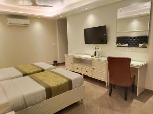 - une chambre avec 2 lits, un bureau et une télévision dans l'établissement THE HERITAGE, à Gurgaon
