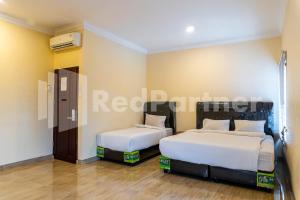 a bedroom with two beds in a room at Adam Malik Guesthouse near Regale ICC Medan Mitra RedDoorz in Medan