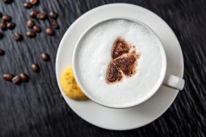 a cup of coffee on a plate with coffee beans at Al Khoory Inn Bur Dubai in Dubai