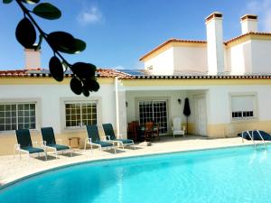 a swimming pool with chairs and a house at Villa Casa Dina in Casal da Lagoa Seca