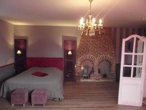 a bedroom with a bed and a brick fireplace at La Chaussee d'Olivet en Mayenne in Olivet