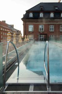 哥本哈根的住宿－Villa Copenhagen，一个空的游泳池,有一座建筑的背景