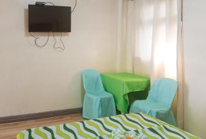 ダバオシティにあるIDMAT INNの青い椅子2脚、緑のテーブル、テレビが備わる客室です。