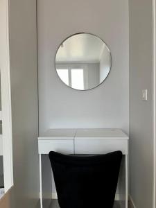 a white vanity with a mirror and a black chair at Appartement situé au centre ville d’alfortville in Alfortville