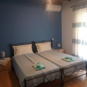 a blue bedroom with a bed with two green slippers on it at Armiriki Apartments in Korakokhórion