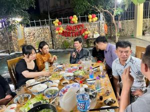 un grupo de personas sentadas alrededor de una mesa comiendo comida en Garden House Nha Trang en Nha Trang