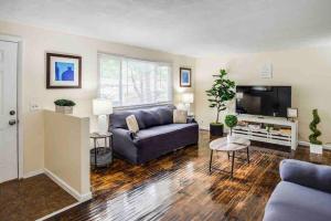 a living room with a couch and a flat screen tv at Stunning Ranch Mins from RIT/Airport/U of R/DWTN in Rochester