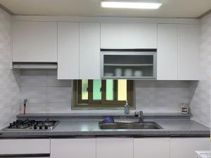 a kitchen with white cabinets and a sink at Lakeside Mirinae Villa in Anseong
