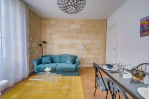 a living room with a blue couch and a table at Chez Jeanne - Appartement Hyper Centre in Bordeaux +6 photos