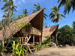 a house on the beach with palm trees at Kanipa Beach Glamping in El Nido