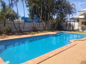 a swimming pool in a yard with a fence and trees at Bargara Beach Motor Inn budget accommodation pet friendly on application in Bargara