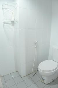 a white bathroom with a toilet and a hose at Kia Servised Apartmen at Grand Sentraland Karawang in Karawang