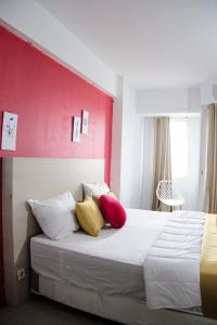 Kia Servised Apartmen at Grand Sentraland Karawang في كراوانغ: غرفة نوم بسرير ومخدات حمراء وصفراء