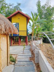 una casa gialla con un sentiero che la porta di Homestay Nang Nghieng a Kon Tum