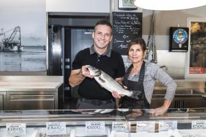 Un uomo e una donna che tengono un pesce in una cucina di Casa Mafalda a Chioggia