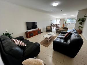 a living room with a black leather couch and a tv at Downtown Narrabri in Narrabri