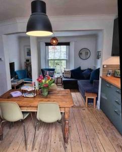 een keuken en een woonkamer met een houten tafel en stoelen bij Mermaid Cottage Teignmouth by the beach SLEEPS 7 in Teignmouth