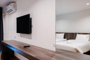 um quarto com uma cama e uma televisão na parede em JS HOTEL em Hat Yai