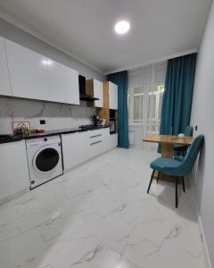 uma cozinha com armários brancos e uma mesa com uma cadeira azul em К7 family em Atyrau