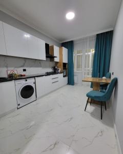 a kitchen with white cabinets and a table with a blue chair at К7 family in Atyraū