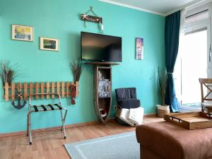 uma sala de estar com uma televisão de ecrã plano numa parede azul em 13-18, sehr Strandnah, im Herzen Westerlands, Westbalkon, 1 Zi em Westerland