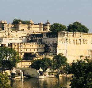 a large building sitting on the side of a river at Hostel Nirvana in Udaipur