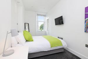 a white bedroom with a bed and a tv at One bed apartment in the heart of Innerleithen in Innerleithen