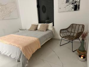 a white bedroom with a bed and a chair at Villa luv in Atlit