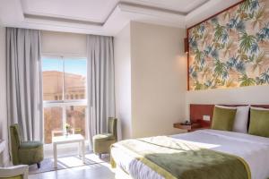 马拉喀什Hotel Safia的一间酒店房间，里面有一张床和一扇大窗户。