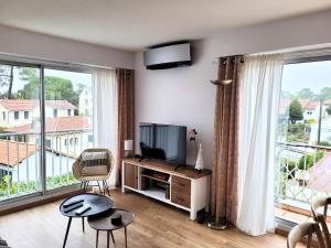 a living room with a television and large windows at Havre de paix 4 étoiles, à 100 mètres de la plage in Saint-Georges-de-Didonne