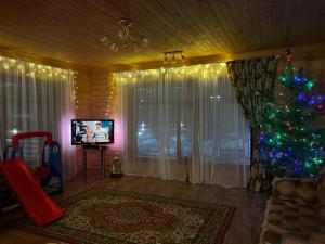 a living room with a christmas tree and a television at Гостевой дом Alai in Shchūchīnsk
