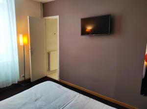 a bedroom with a flat screen tv on the wall at Hôtel La Rivière in Entraygues-sur-Truyère