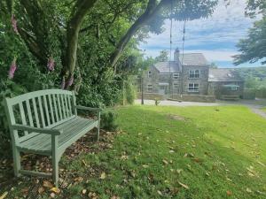 a bench sitting in the grass in front of a house at The Old Farmhouse in Michaelstow