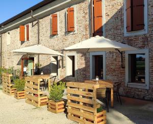 two tables and umbrellas in front of a building at Mulino Delle Valli in Cerea