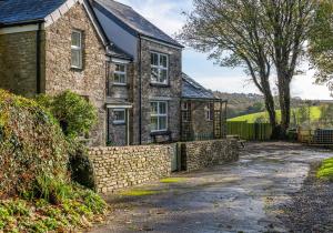a stone house with a stone wall and a driveway at The Old Farmhouse in Michaelstow