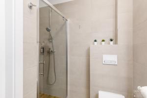 eine Dusche mit Glastür im Badezimmer in der Unterkunft KOŁOBrzegu Apartamenty by Jantar Apartamenty Kołobrzeg in Kołobrzeg + 61 Fotos