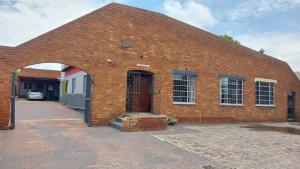 a red brick building with a red door at Jay's Guest House in eMalahleni