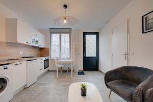 a kitchen and living room with a couch and a table at Les forges 2 pièces RDC in Avoine