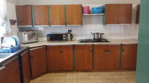 a small kitchen with wooden cabinets and a microwave at Jay's Guest House in eMalahleni