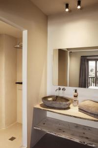 Doryssa Boutique Hotel في بيثاغوريو: حمام مع حوض ومرآة